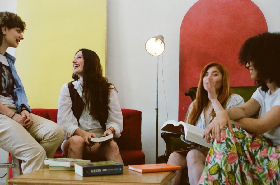 Four friends laughing over books in a bright living room