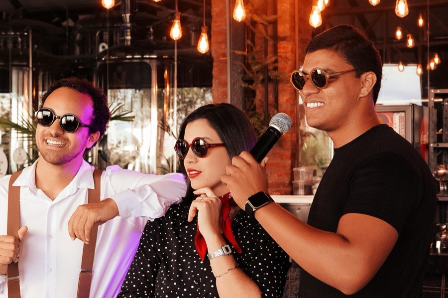 Three friends mid-song at a karaoke bar